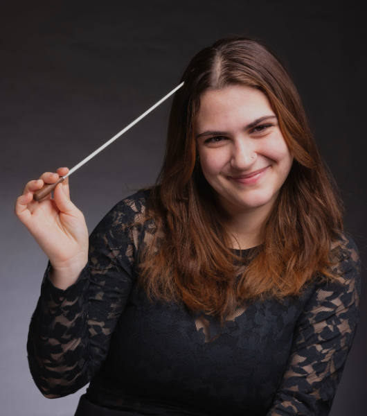Female student composer holding a white conductors baton